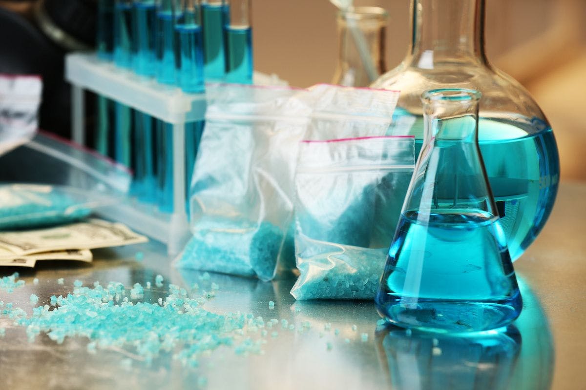 Blue methamphetamine and liquid in flasks on table in laboratory | Image credit: © Africa Studio - stock.adobe.com