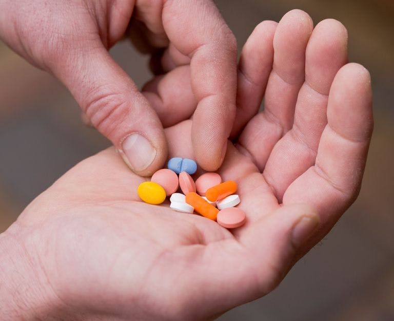person holding different pills in hand
