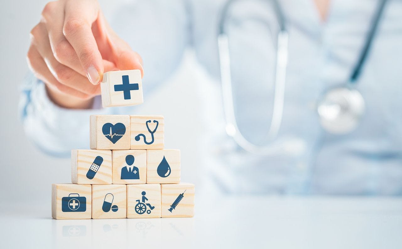 Doctor stacking wooden blocks with health care icons | REDPIXEL - stock.adobe.com