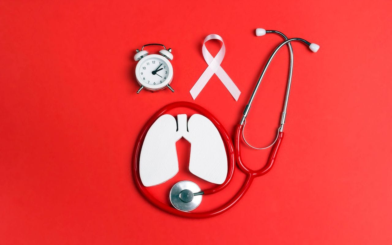 Lung cancer awareness red background with white ribbon, alarm clock and stethoscope: © WindyNight - stock.adobe.com