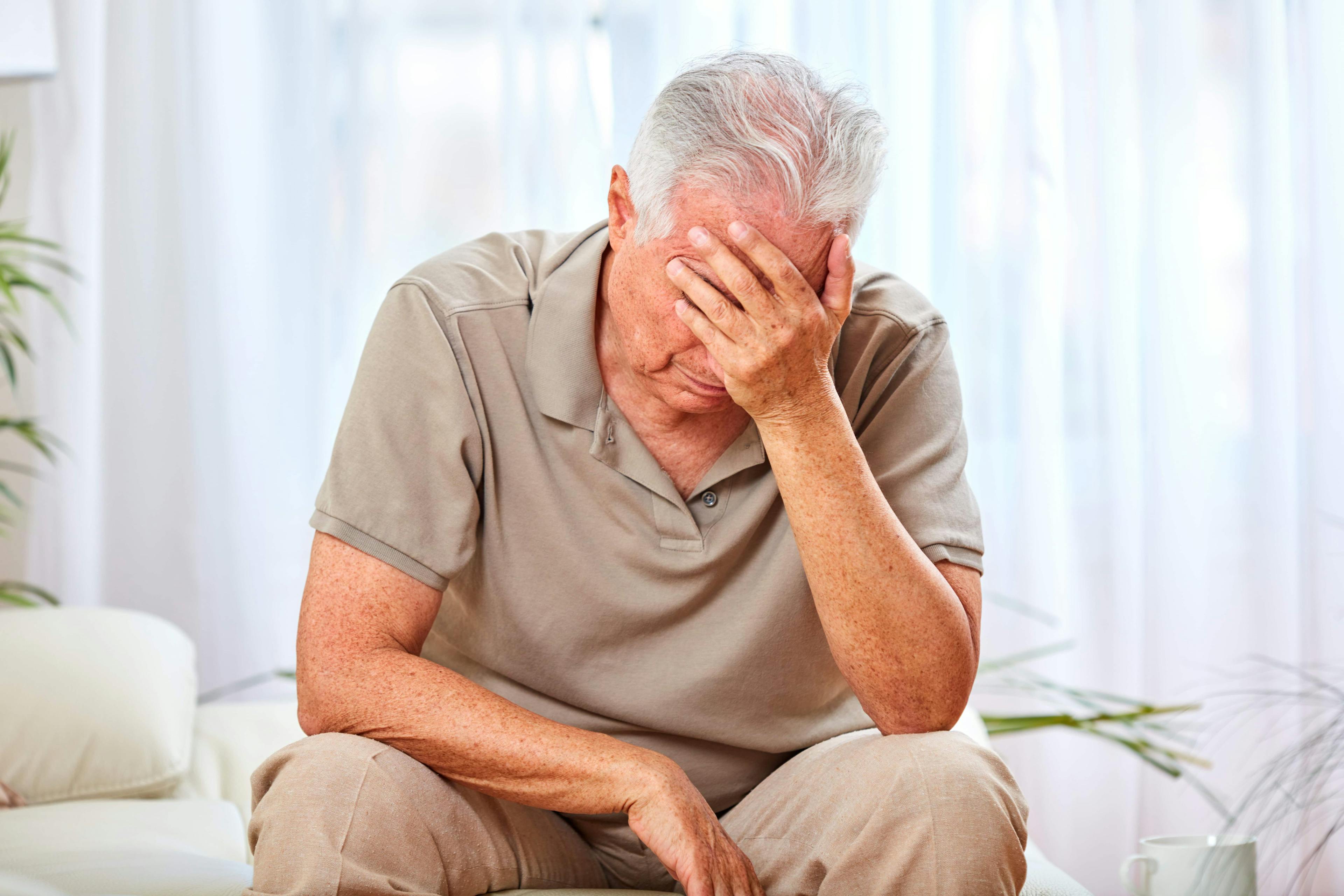 depressed older man sitting with his head in his hand