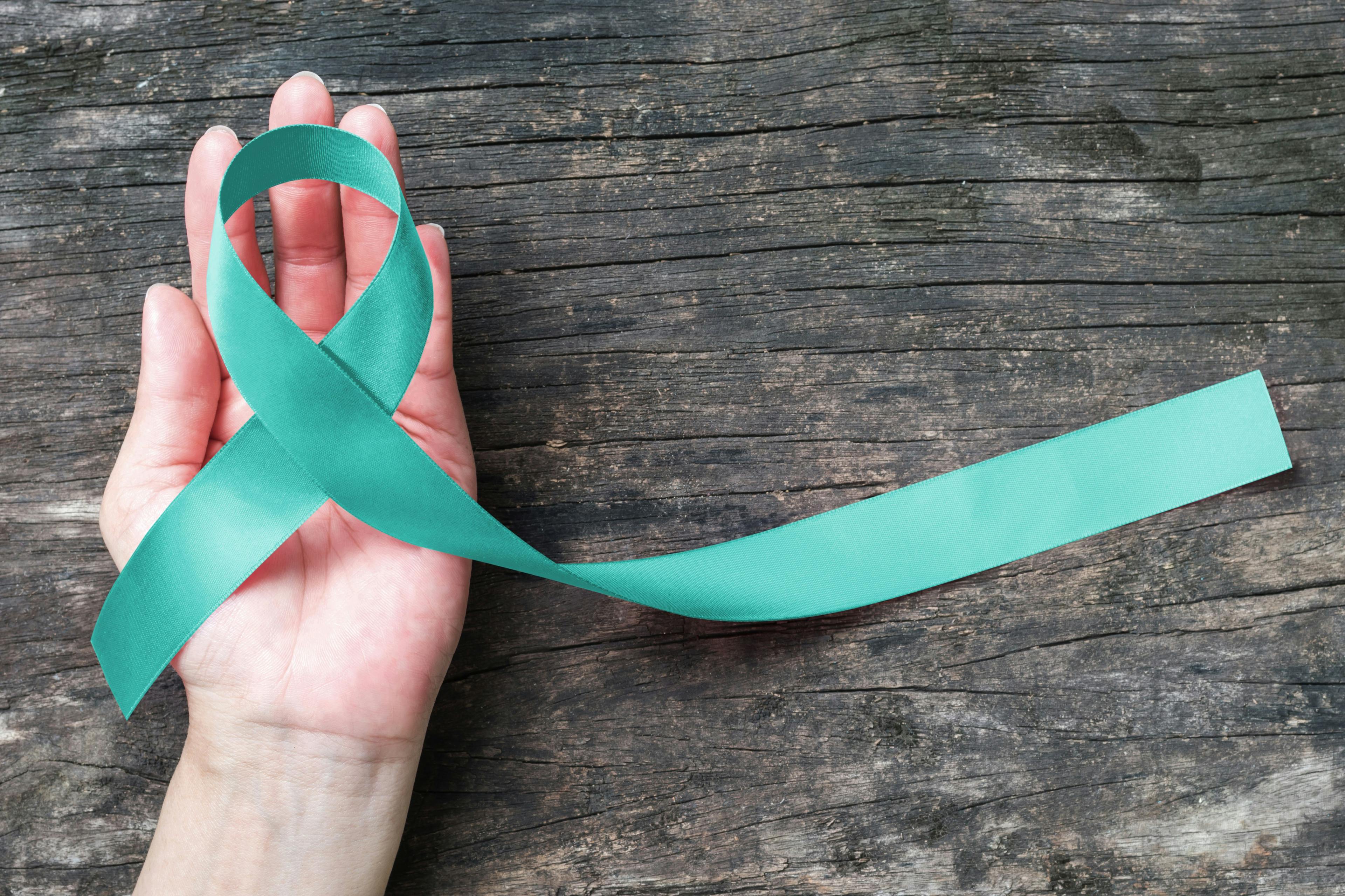 hand holding a teal ribbon