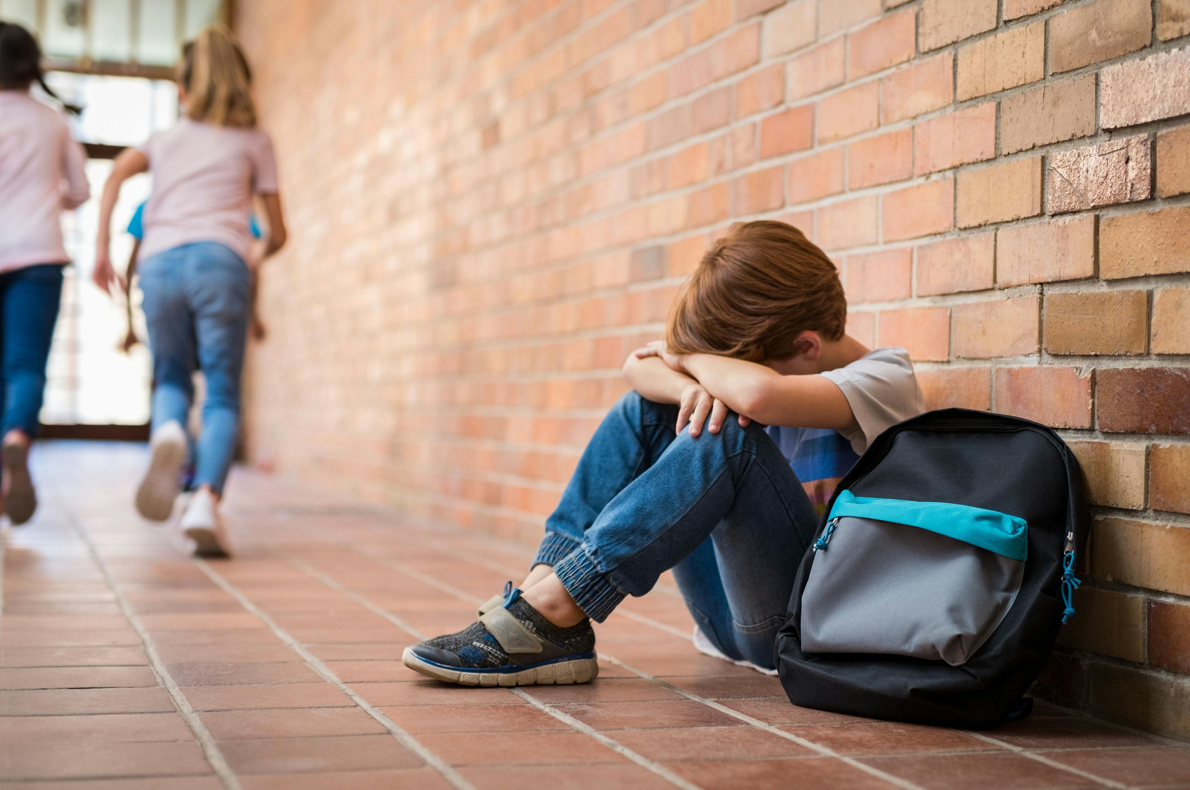 little boy crying at school while group of students run away | Image Credit: Rido - stock.adobe.com