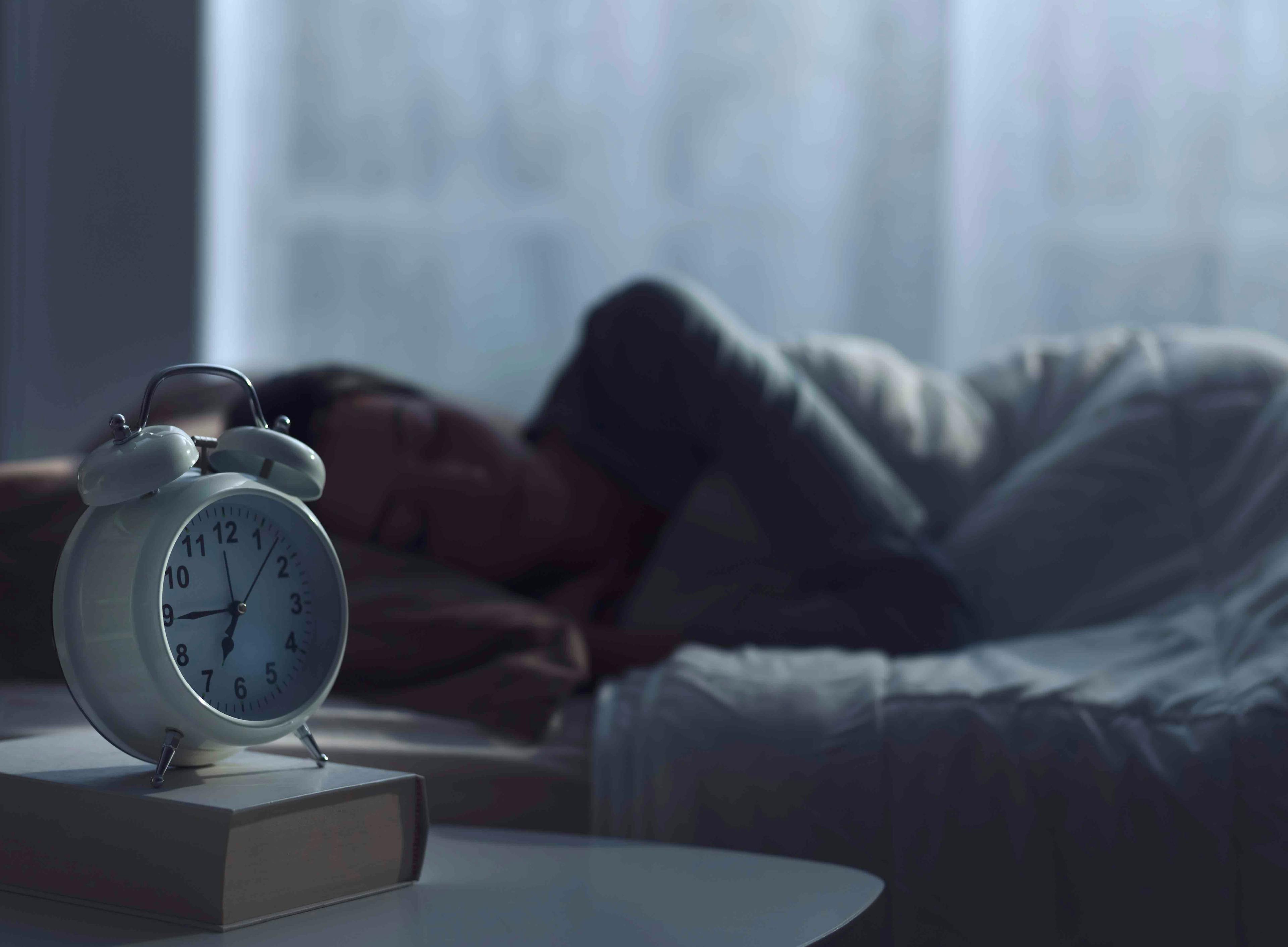 Woman sleeping next to alarm clock - stokkete - stock.adobe.com.jpg