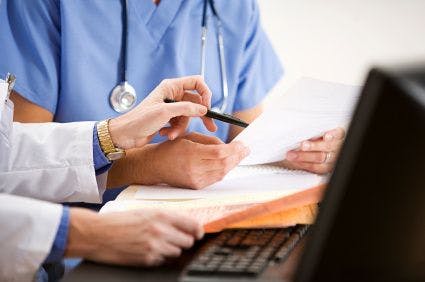 health professionals are working together over a desk with paperwork and a computer
