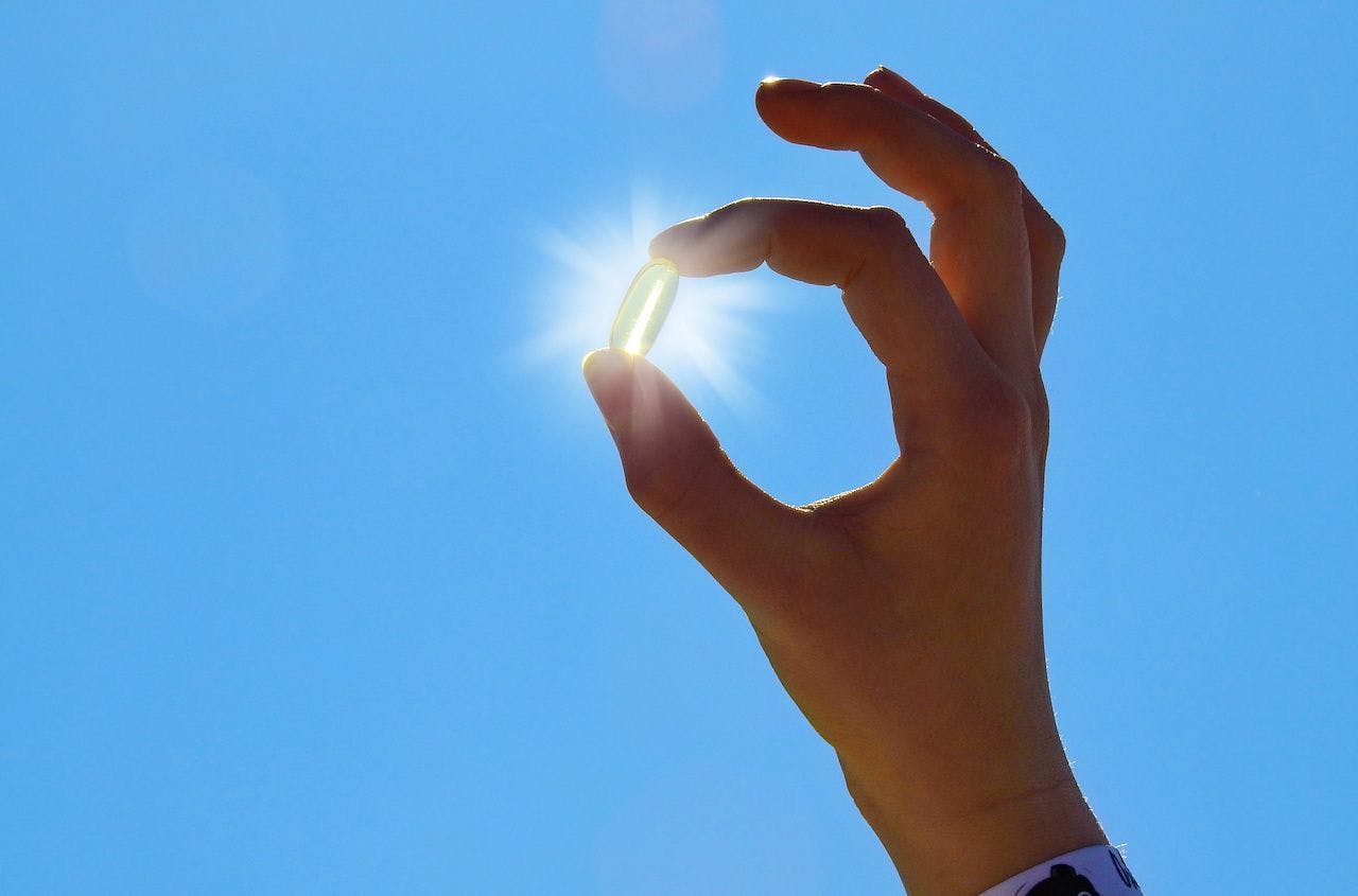 vitamin D capsule held up to the sky