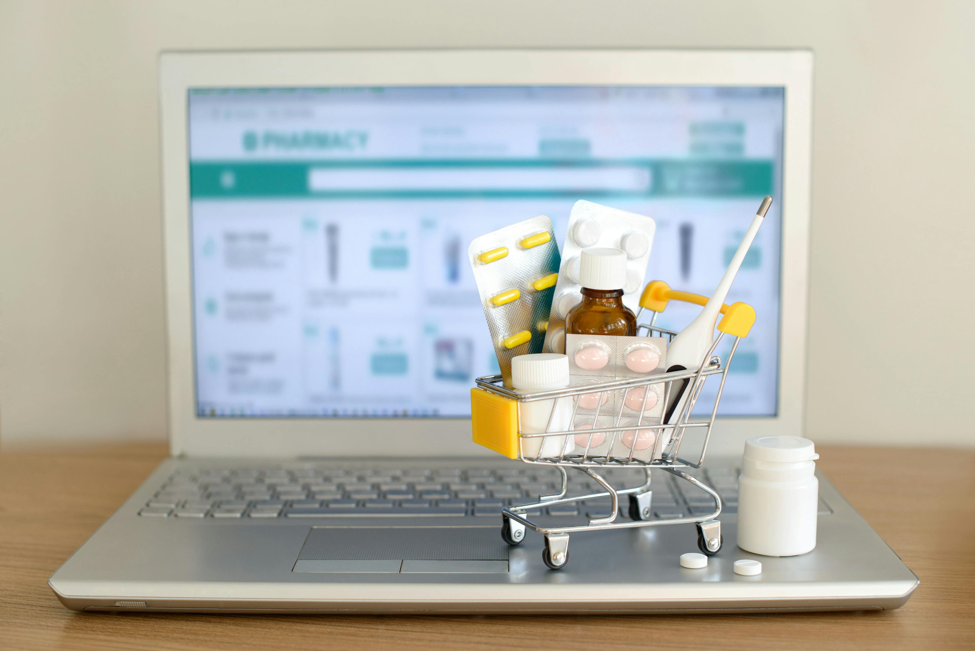 toy shopping cart of medications sitting on a laptop | credit: evso - stock.adobe.com