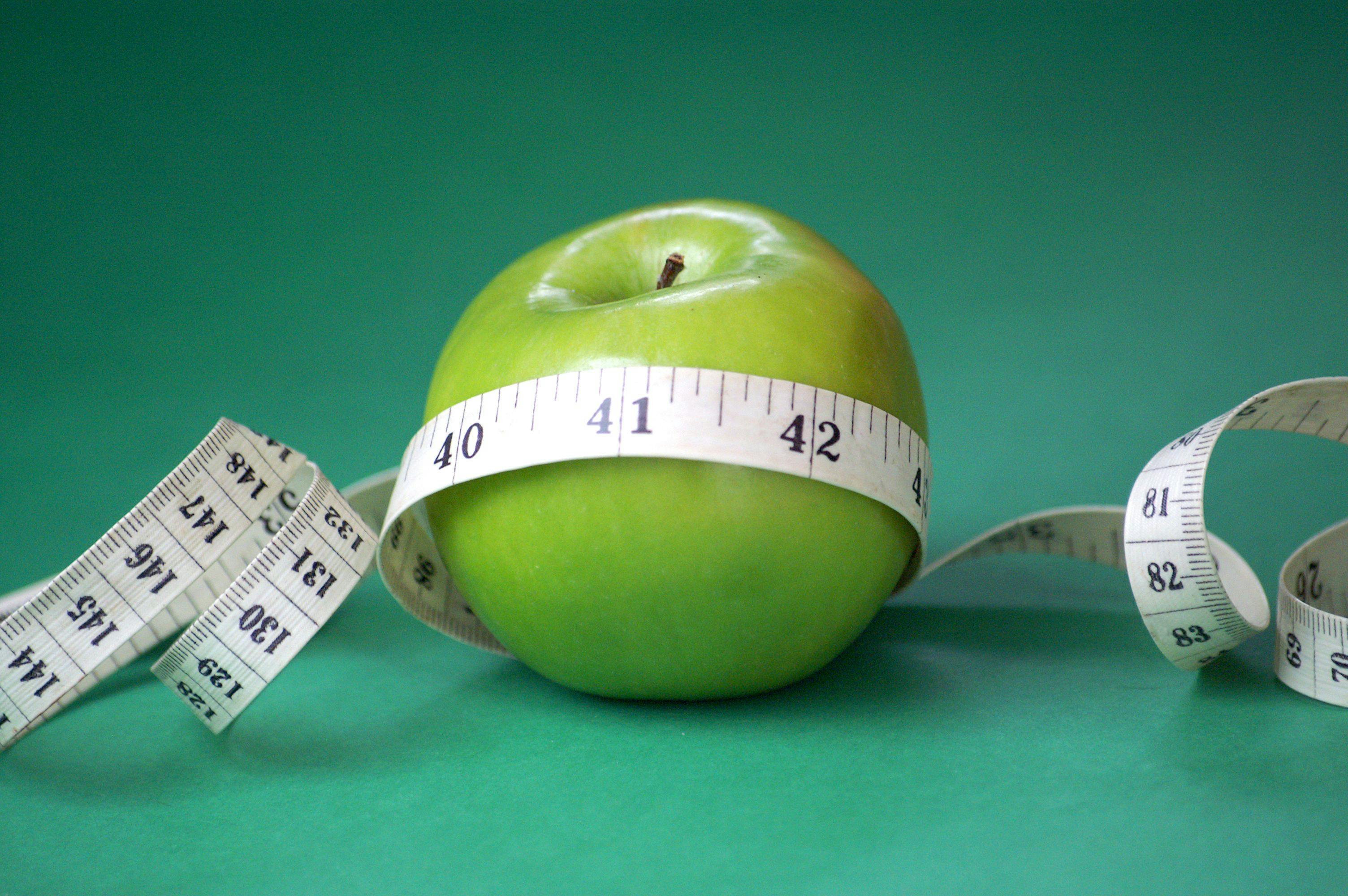 measuring tape surrounding a granny smith apple