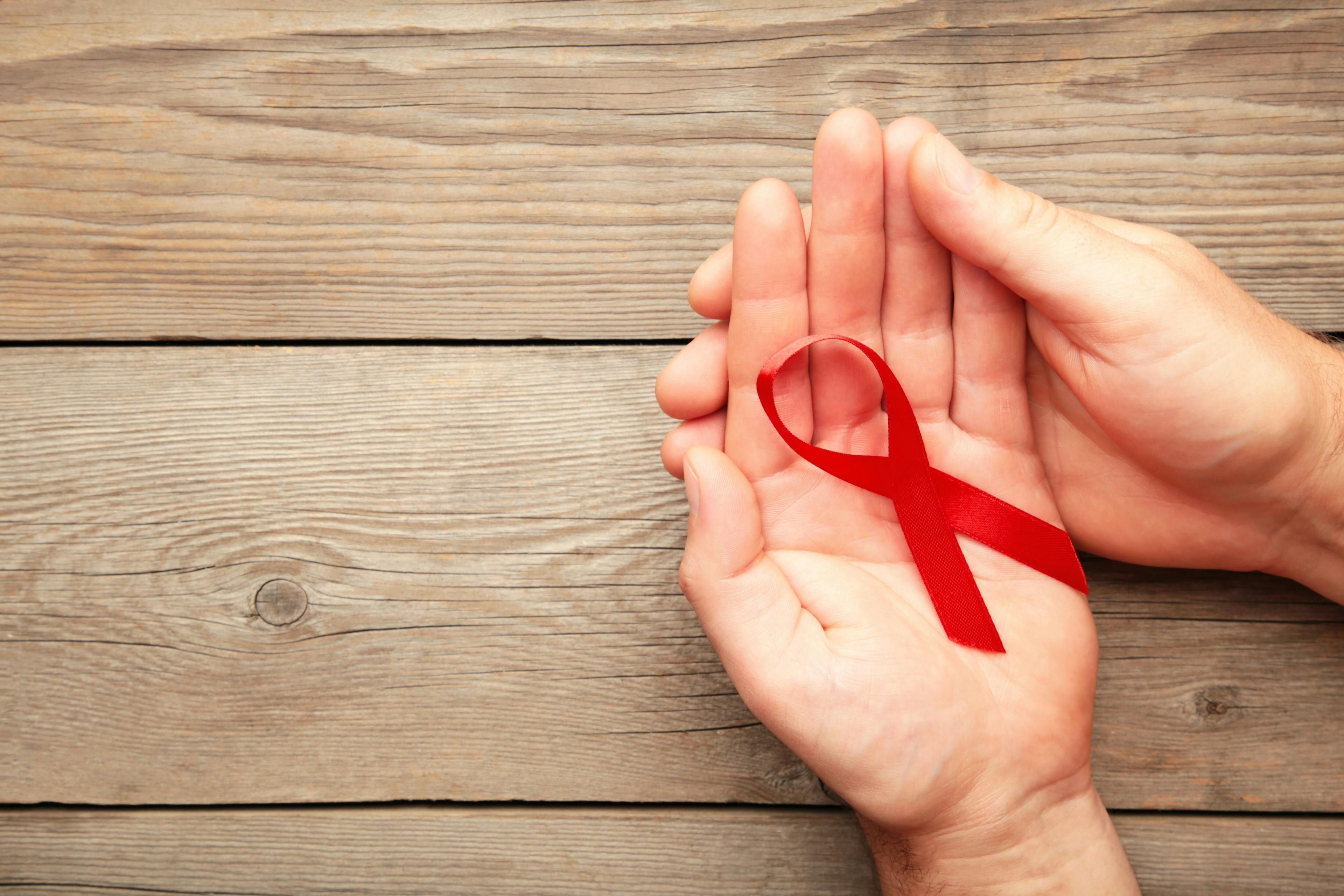A female hands holding an aids red ribbon on grey | Image credit: Mouse family - stock.adobe.com