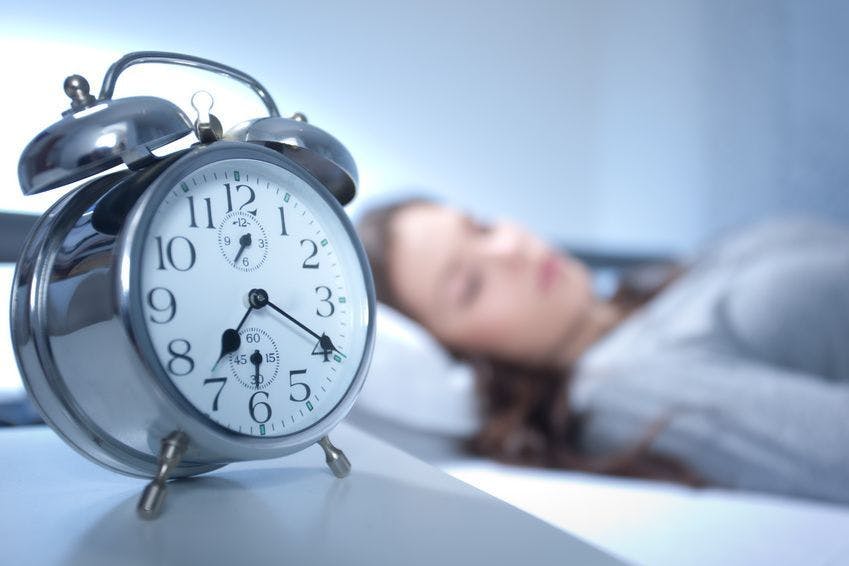 woman sleeping with an alarm clock in focus