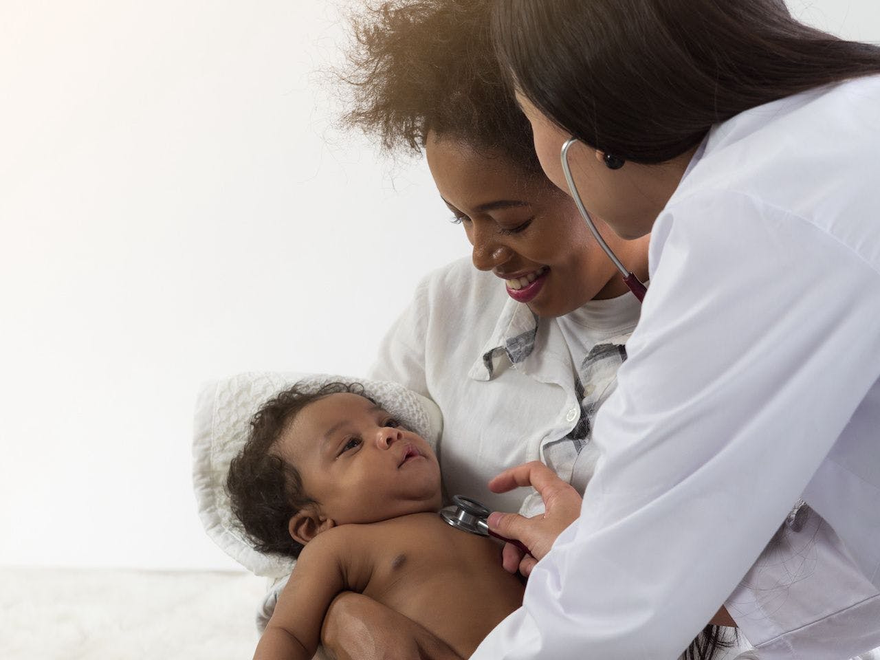 Asian doctor checking on African baby boy in mother's arms. Healthcare for baby concept: © Dollydoll - stock.adobe.com