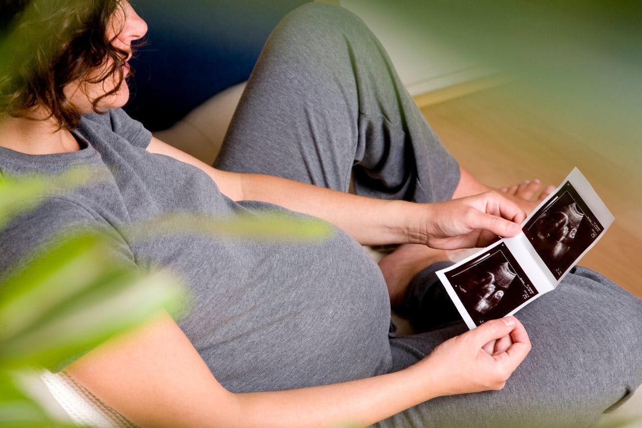 Image of pregnant woman holding ultrasound photos
