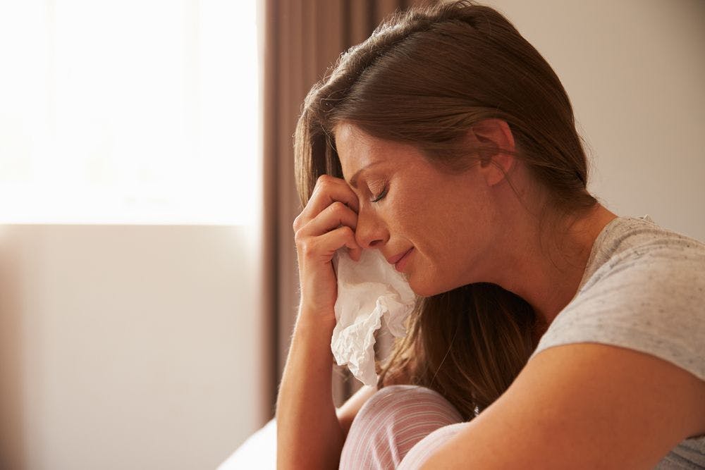 profile shot of a woman crying with a tissue