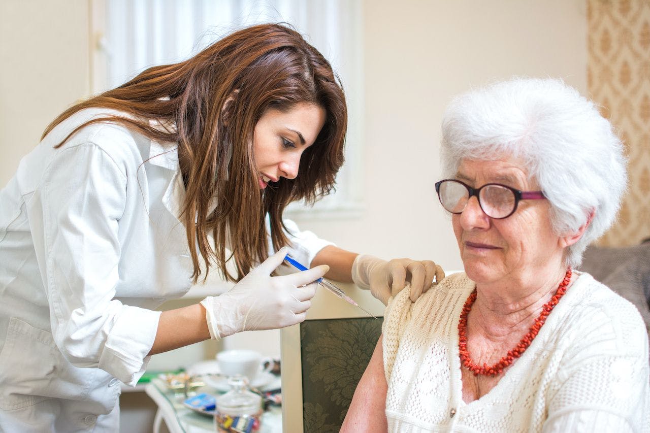 young woman administering a vaccine to an older woman