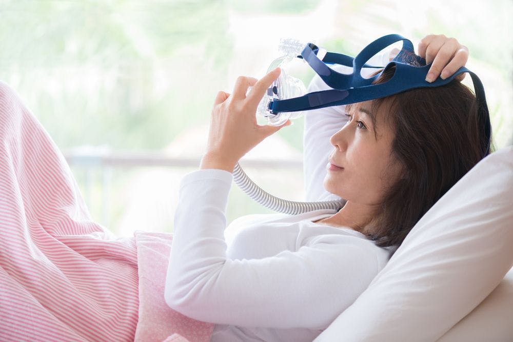 Woman putting on CPAP mask