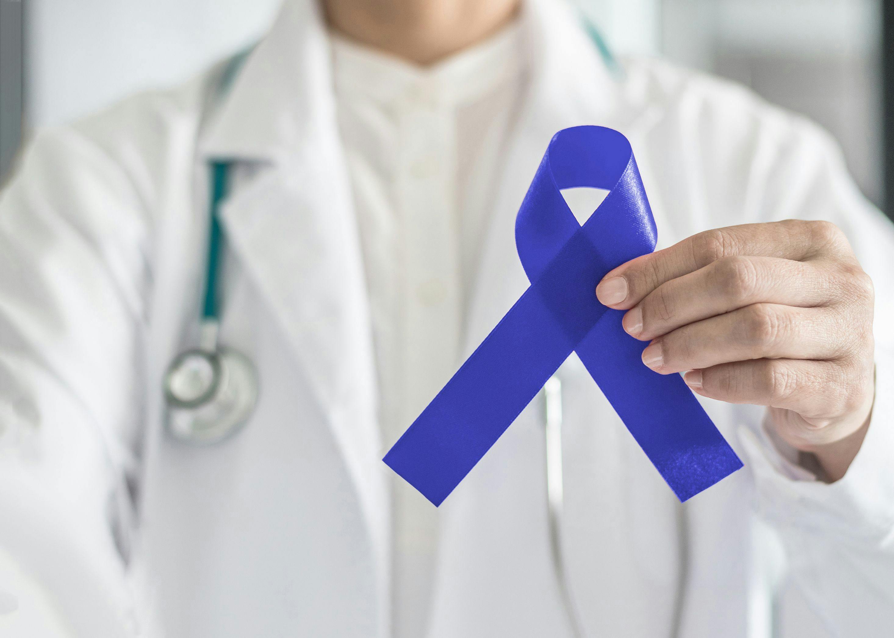 Dark blue ribbon for colon - colorectal cancer awareness on medical doctor's hand support | Image credit: Chinnapong - stock.adobe.com