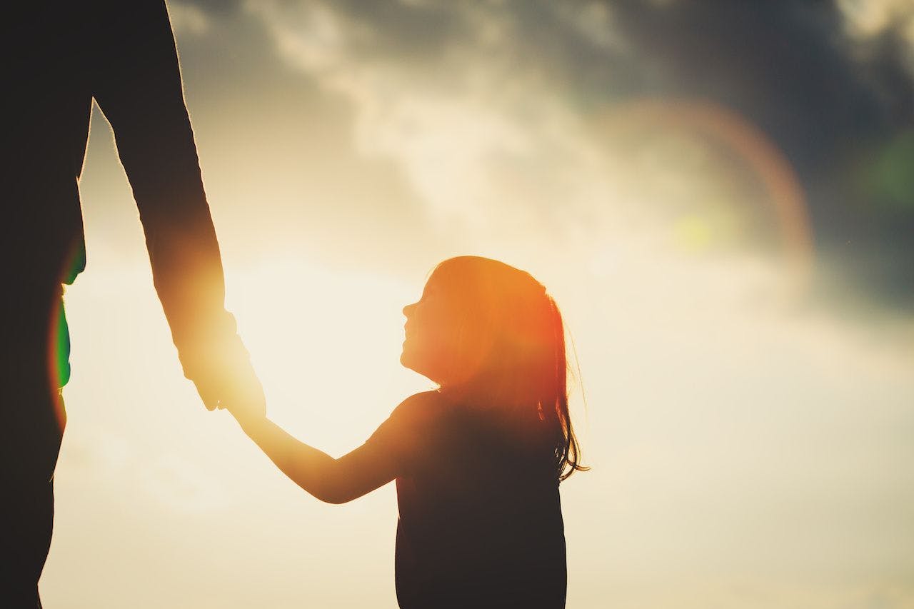 silhouette of little girl holding parent hand at sunse:t ©  nadezhda1906 - stock.adobe.com