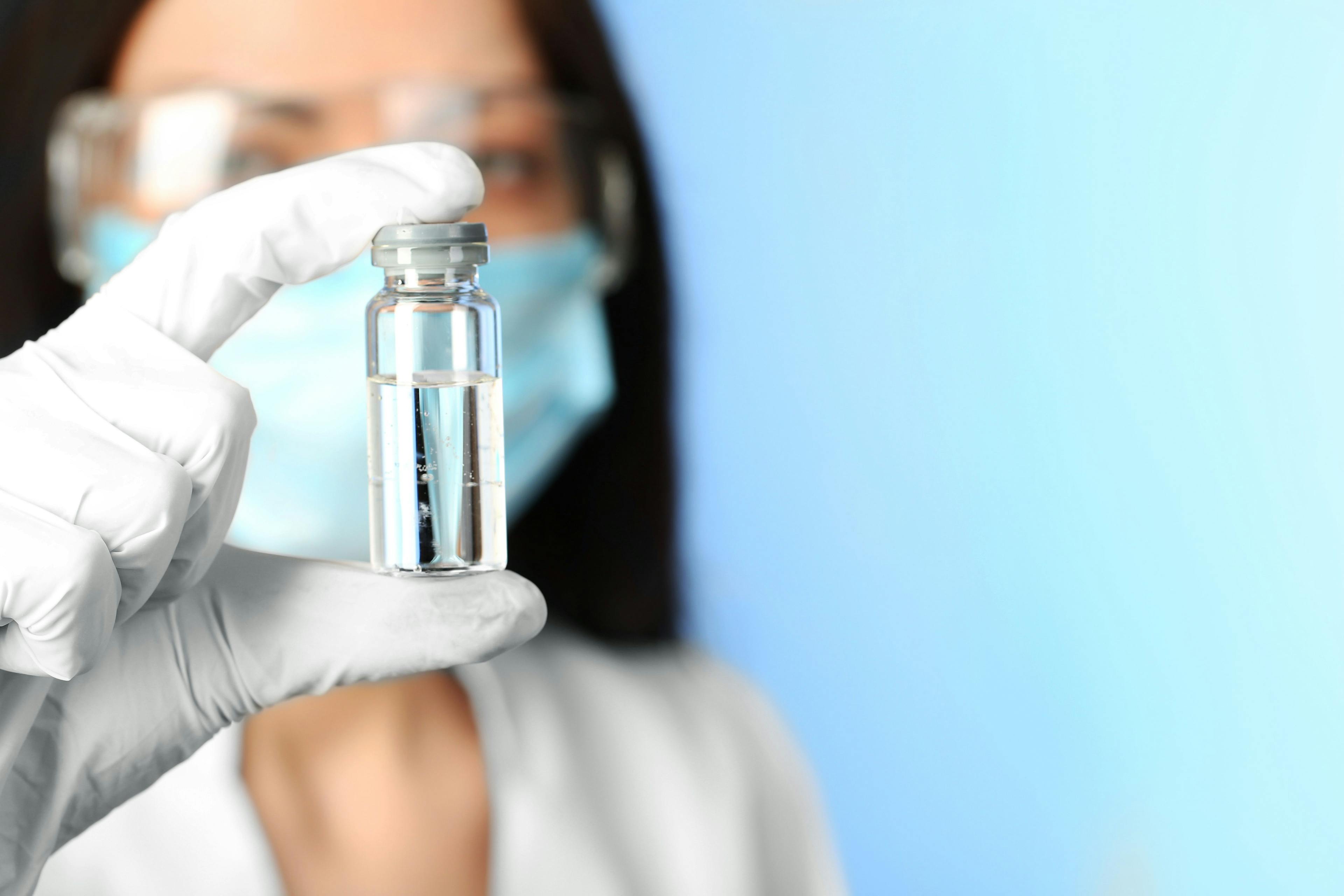 female doctor holding a vial containing a vaccine