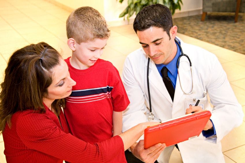 mother, child, and doctor looking at red clipboard