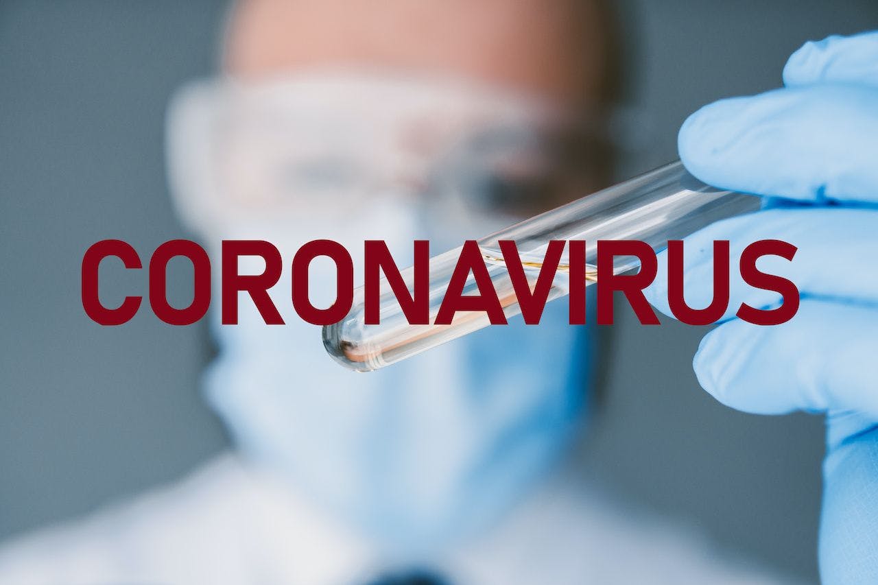 doctor holding a test tube with a clear liquid and the world "coronavirus" superimposed on top