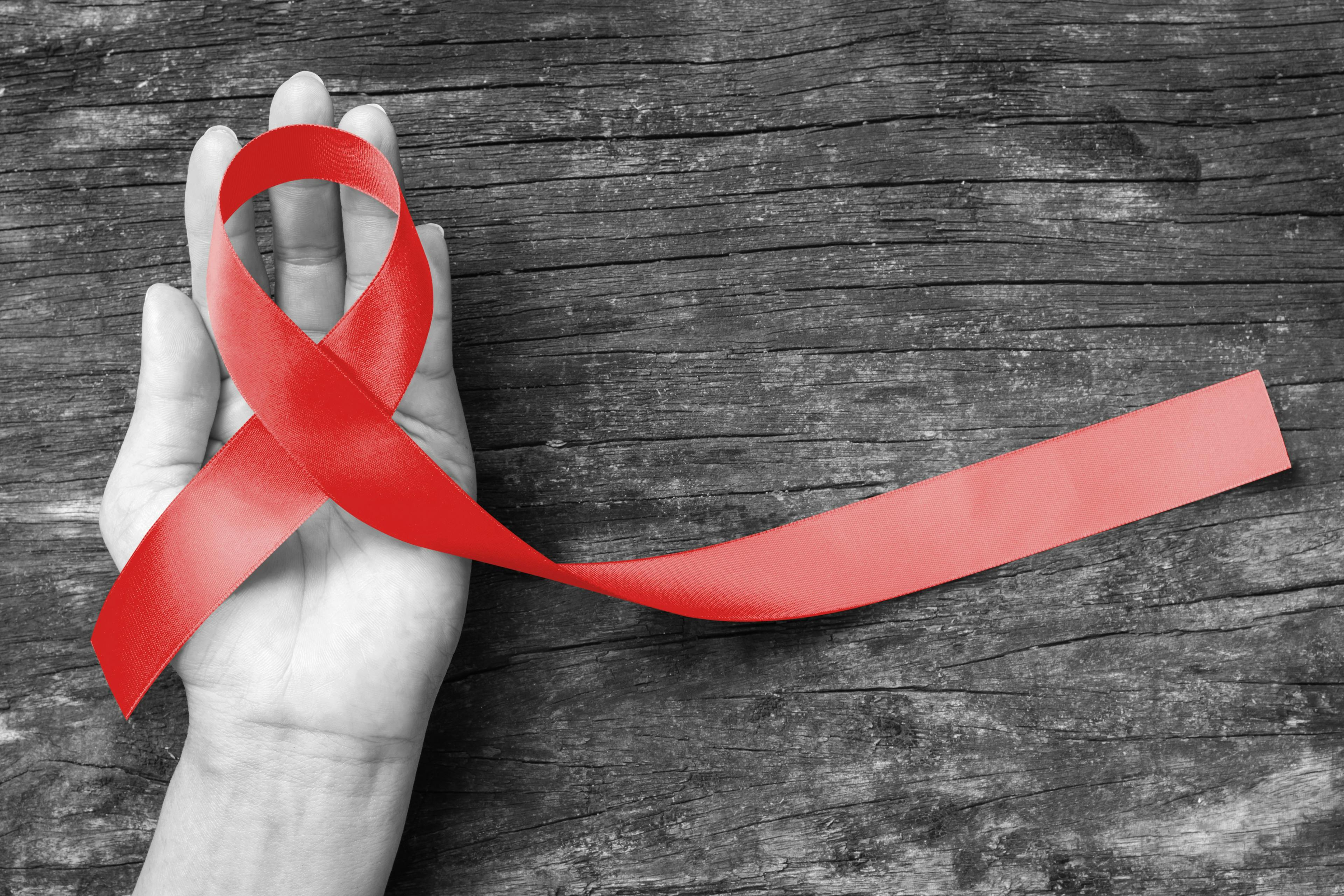 Hand holding HIV red ribbon