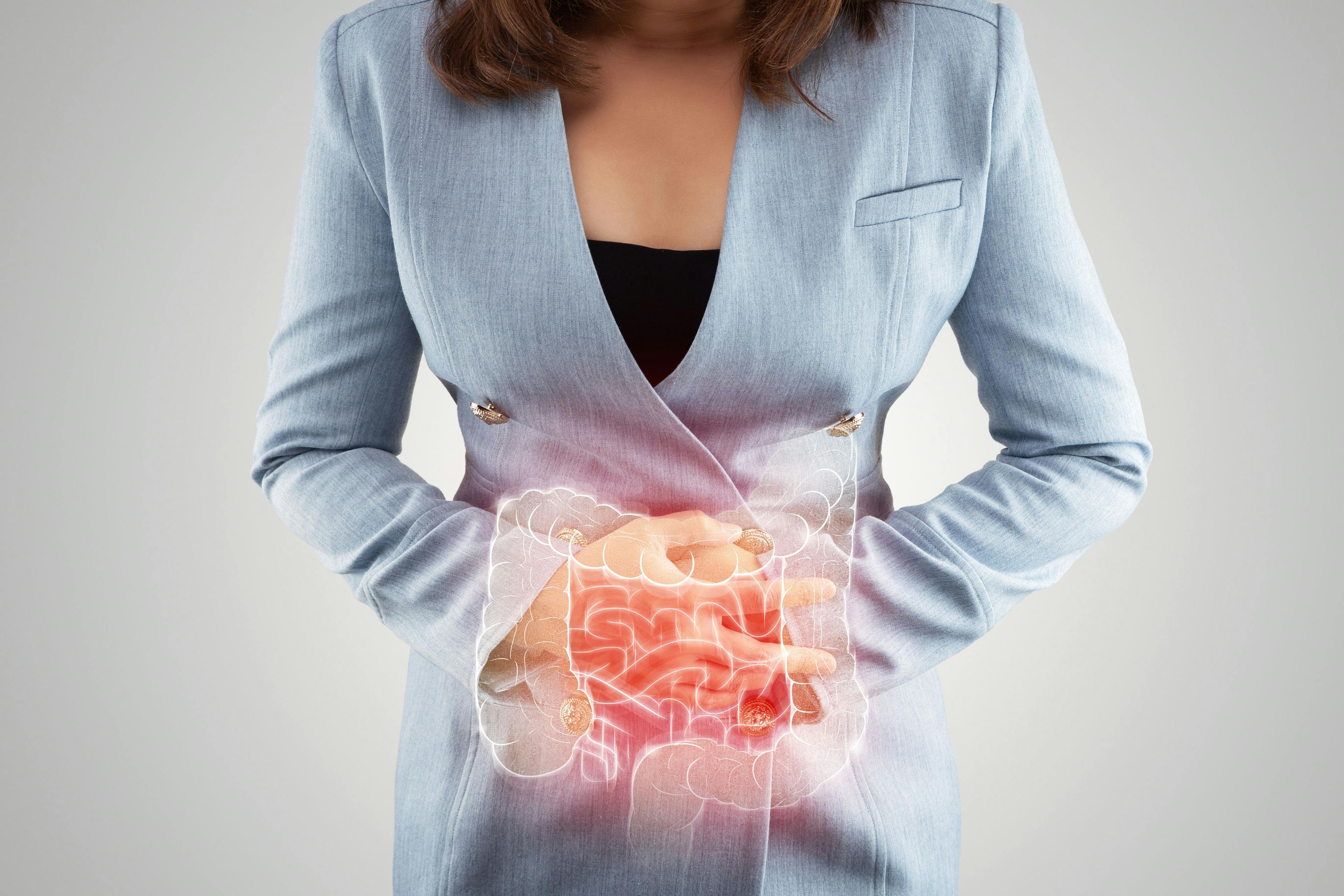 woman in blue suit holding her abdomen in pain | Image Credit: eddows - stock.adobe.com