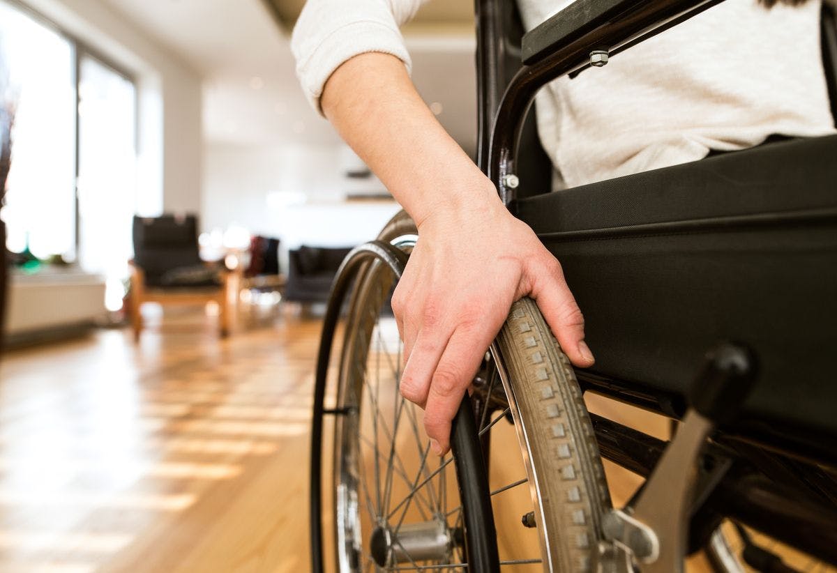 close-up of person using wheelchair with hand on wheel