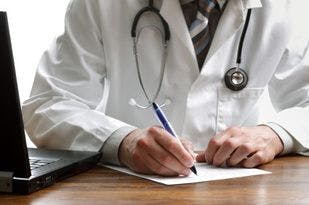 Doctor Looking at Laptop and Writing