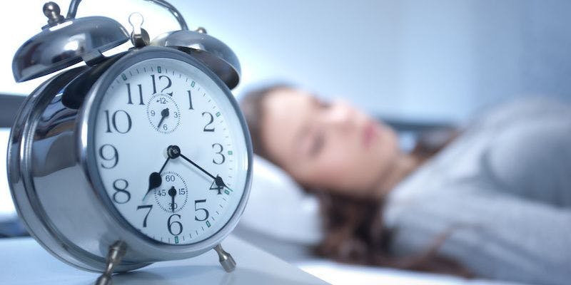 Person sleeping next to a clock.