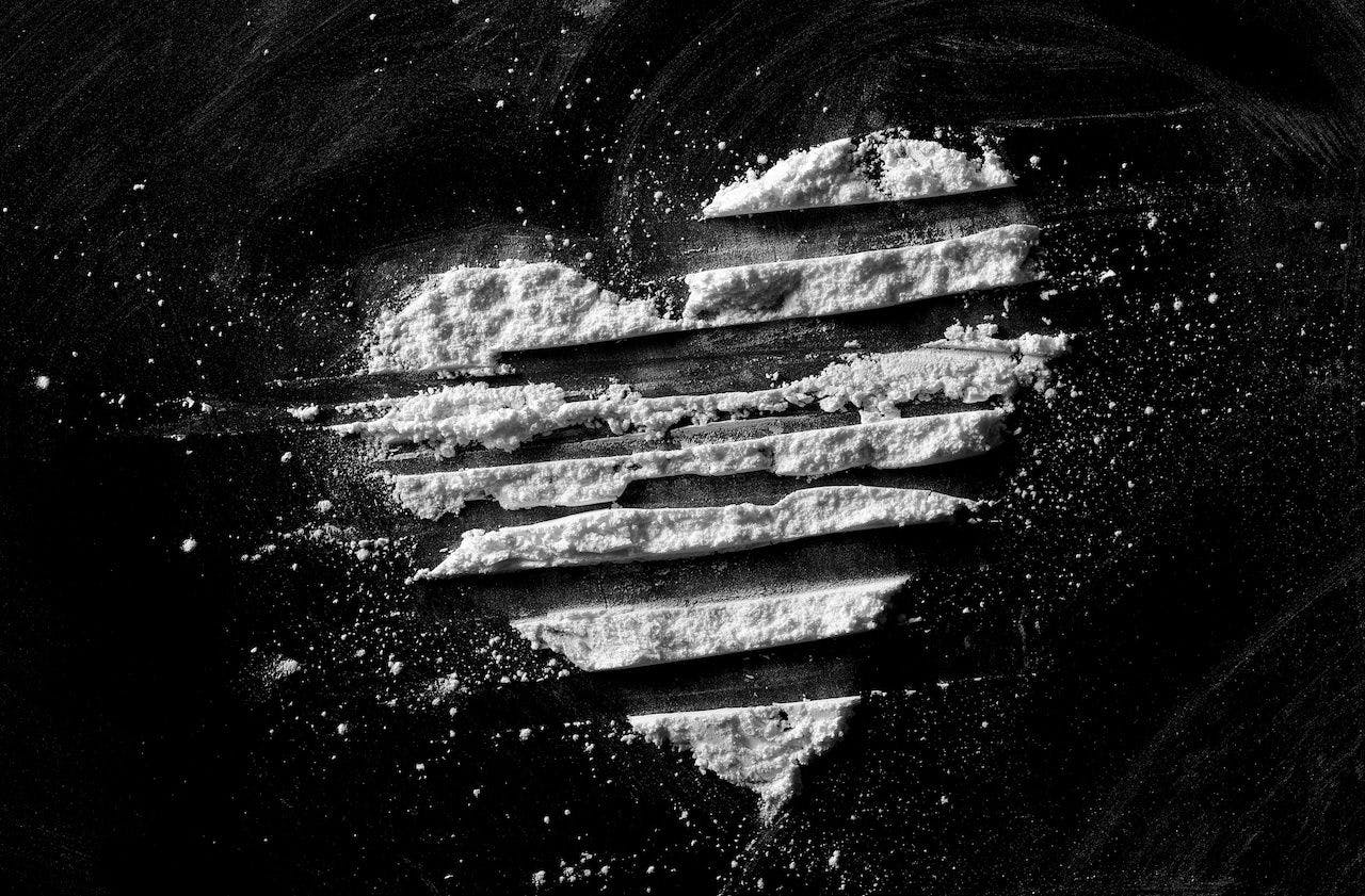 White powder in shape heart, cocaine line isolated on black background, top view, series: © dule964 - stock.adobe.com