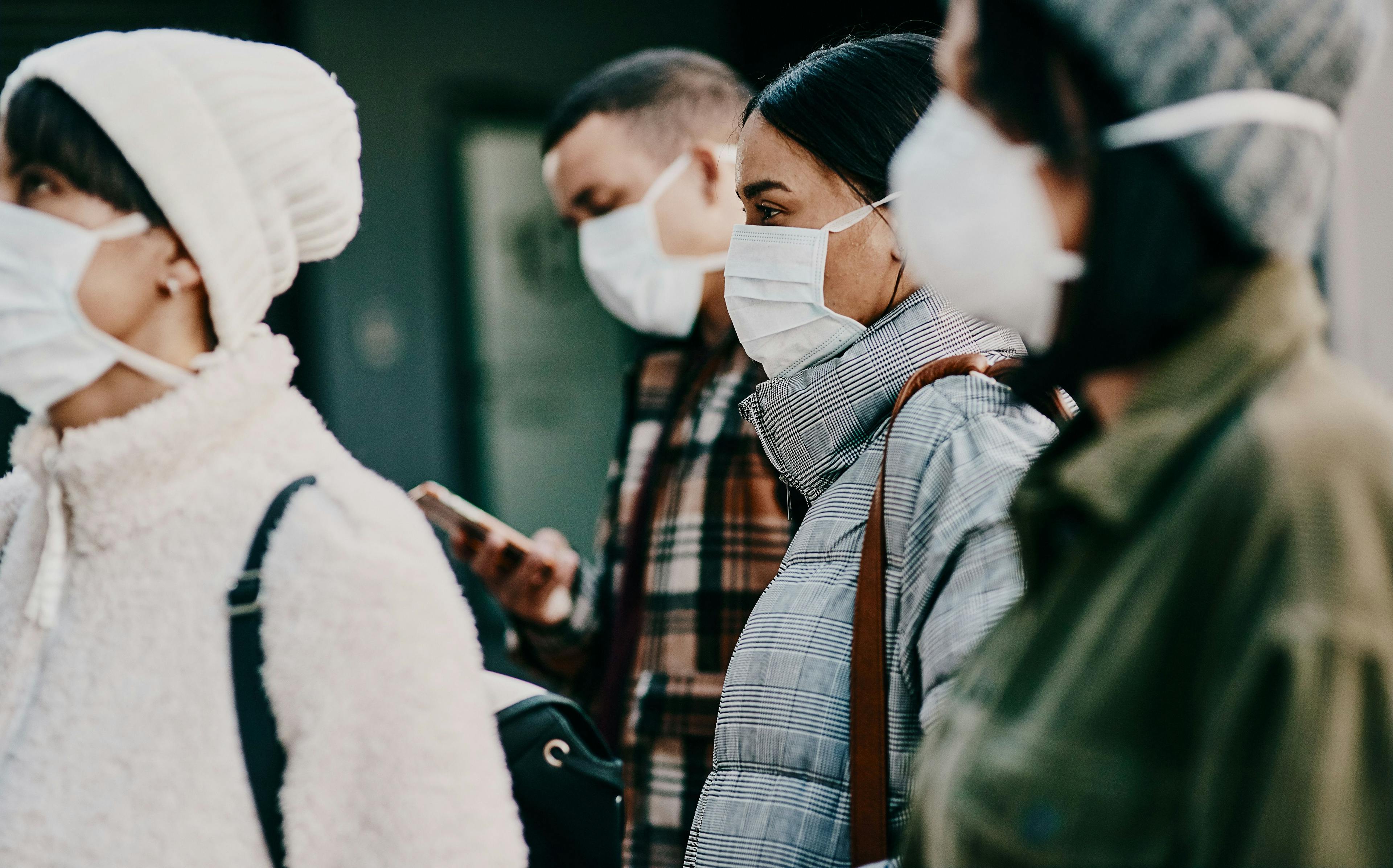 Traveling people wearing face mask in a covid pandemic in crowd, public or airport border with passport or travel restrictions. Foreigners wearing protection to prevent the spread of diseases abroad | Nicholas Felix/peopleimages.com - stock.adobe.com