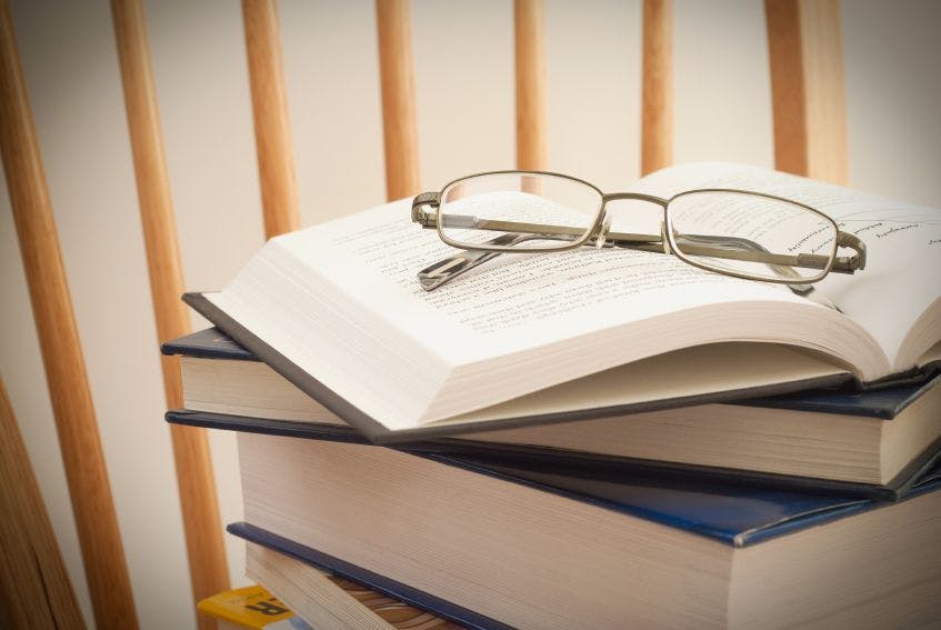 stack of books with reading glasses on top