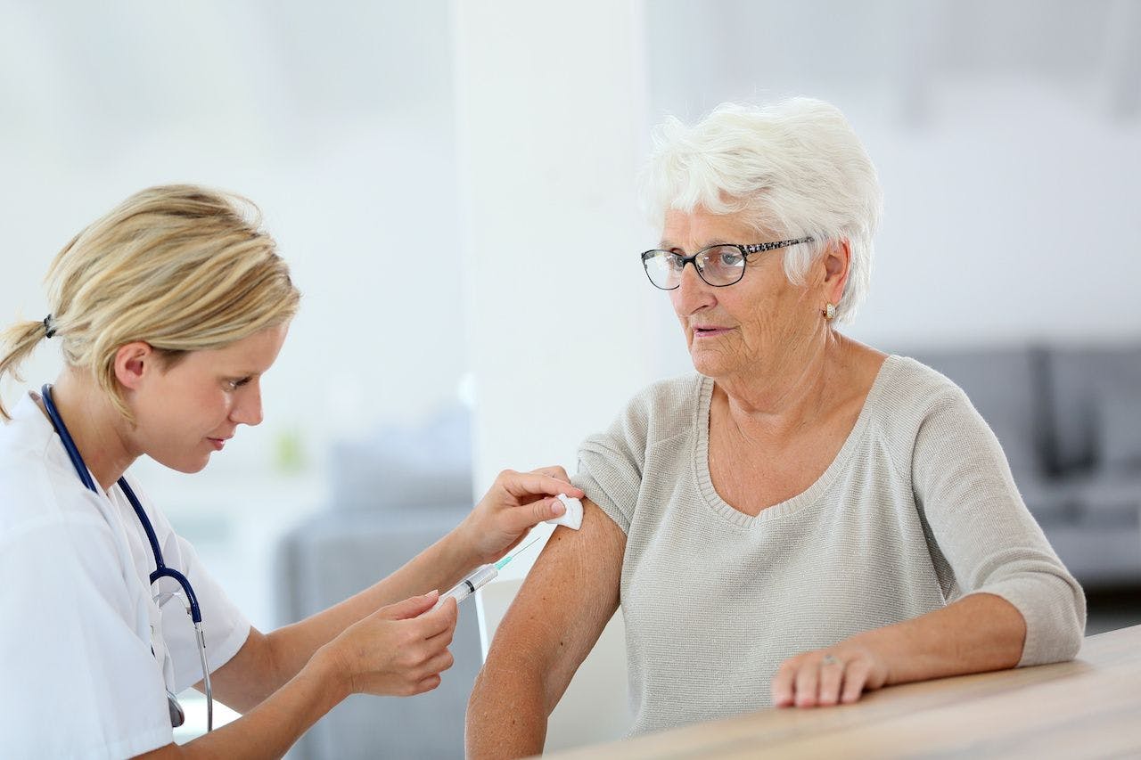 doctor giving a vaccine to an older woman