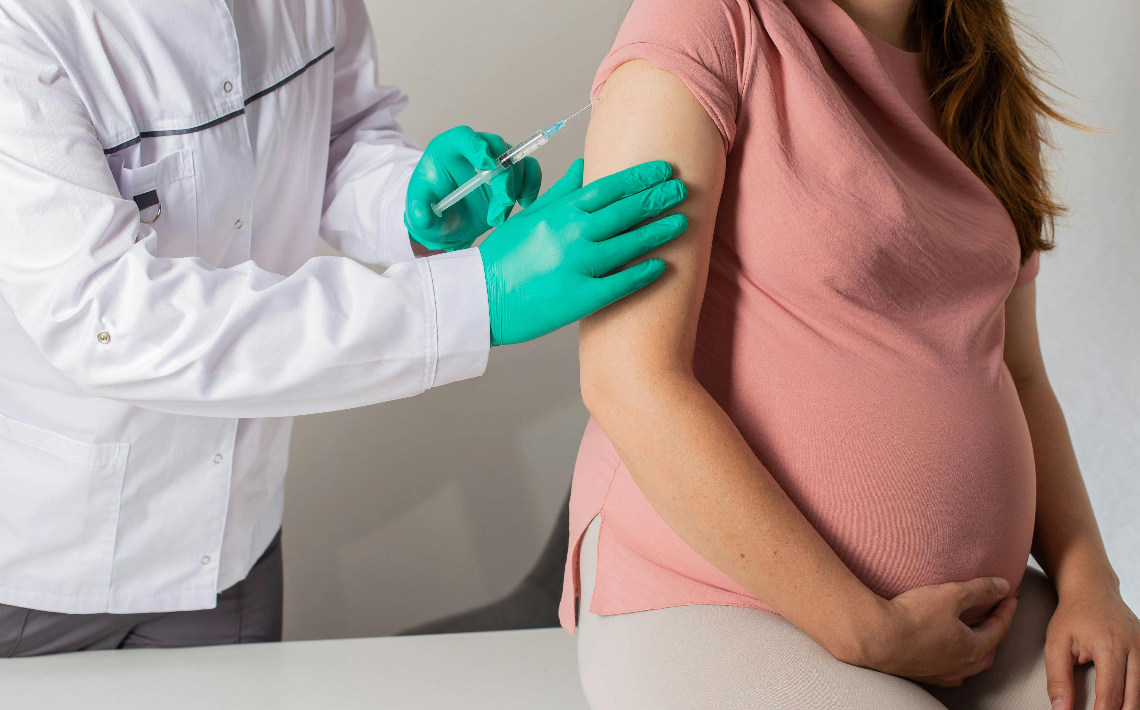 The doctor makes a revaccination of a pregnant girl against coronavirus and influenza. Prophylaxis | Image Credit: HENADZY - stock.adobe.com