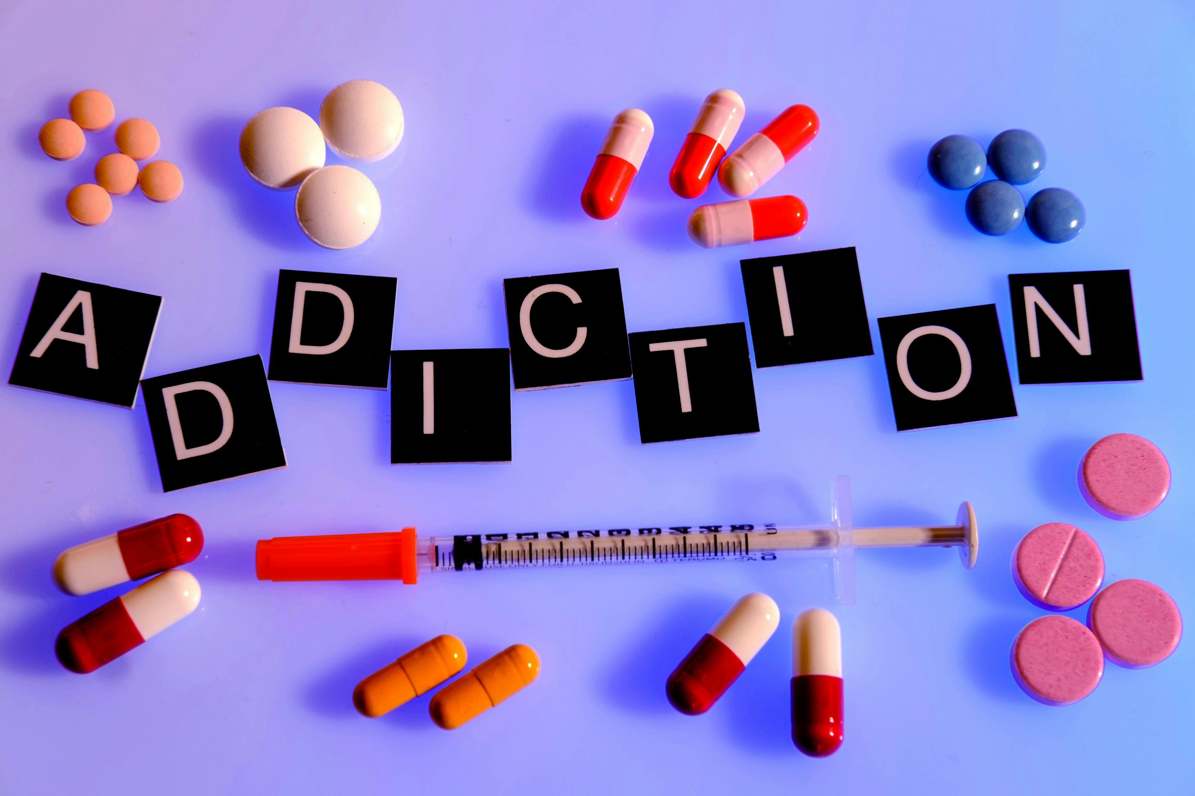 Word "addiction" surrounded by medication, syringe | Image Credit: Belinda Pretorius - stock.adobe.com