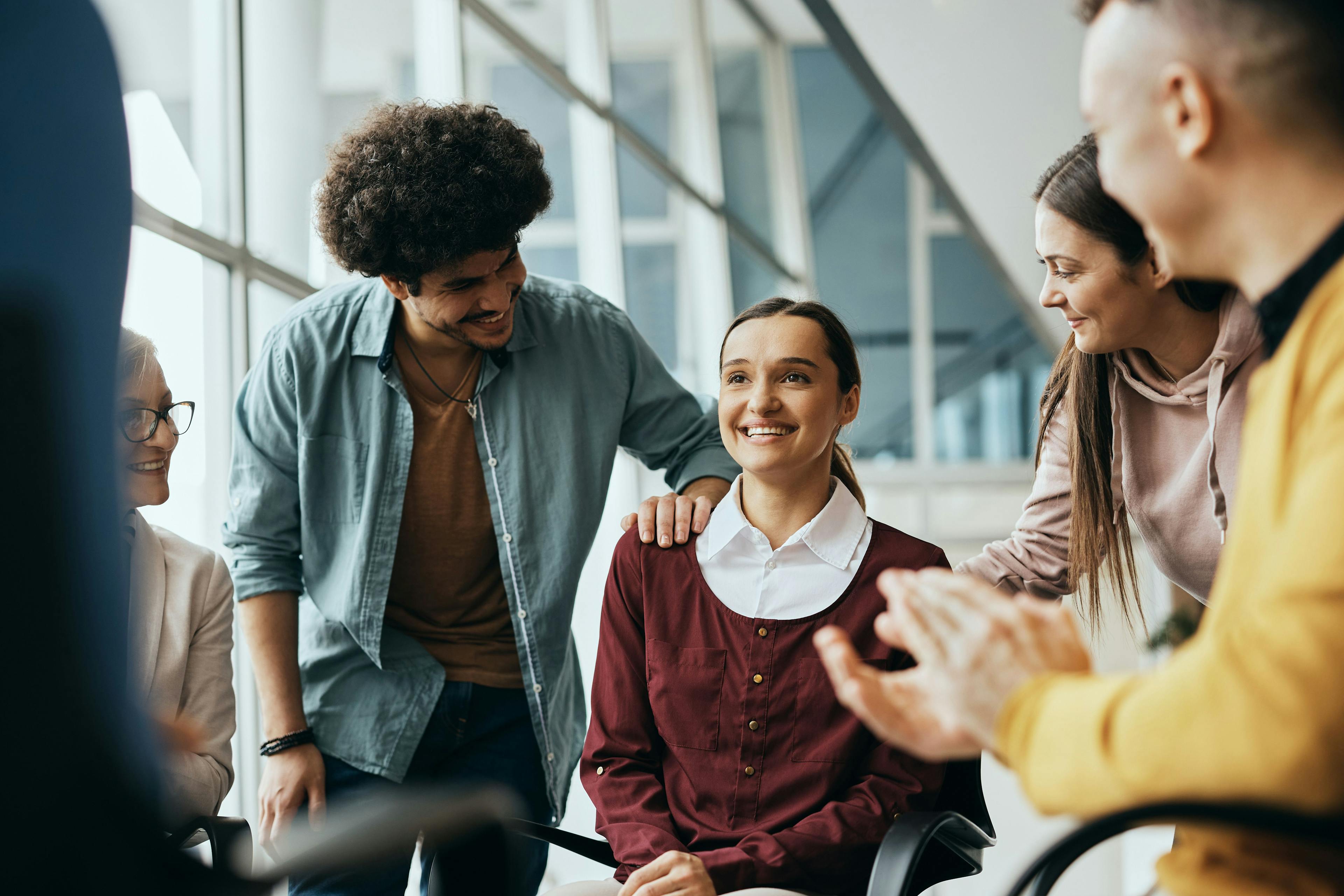 Young happy woman receives support from attenders of group therapy at mental health center | Image Credit: Drazen – stock.adobe.com