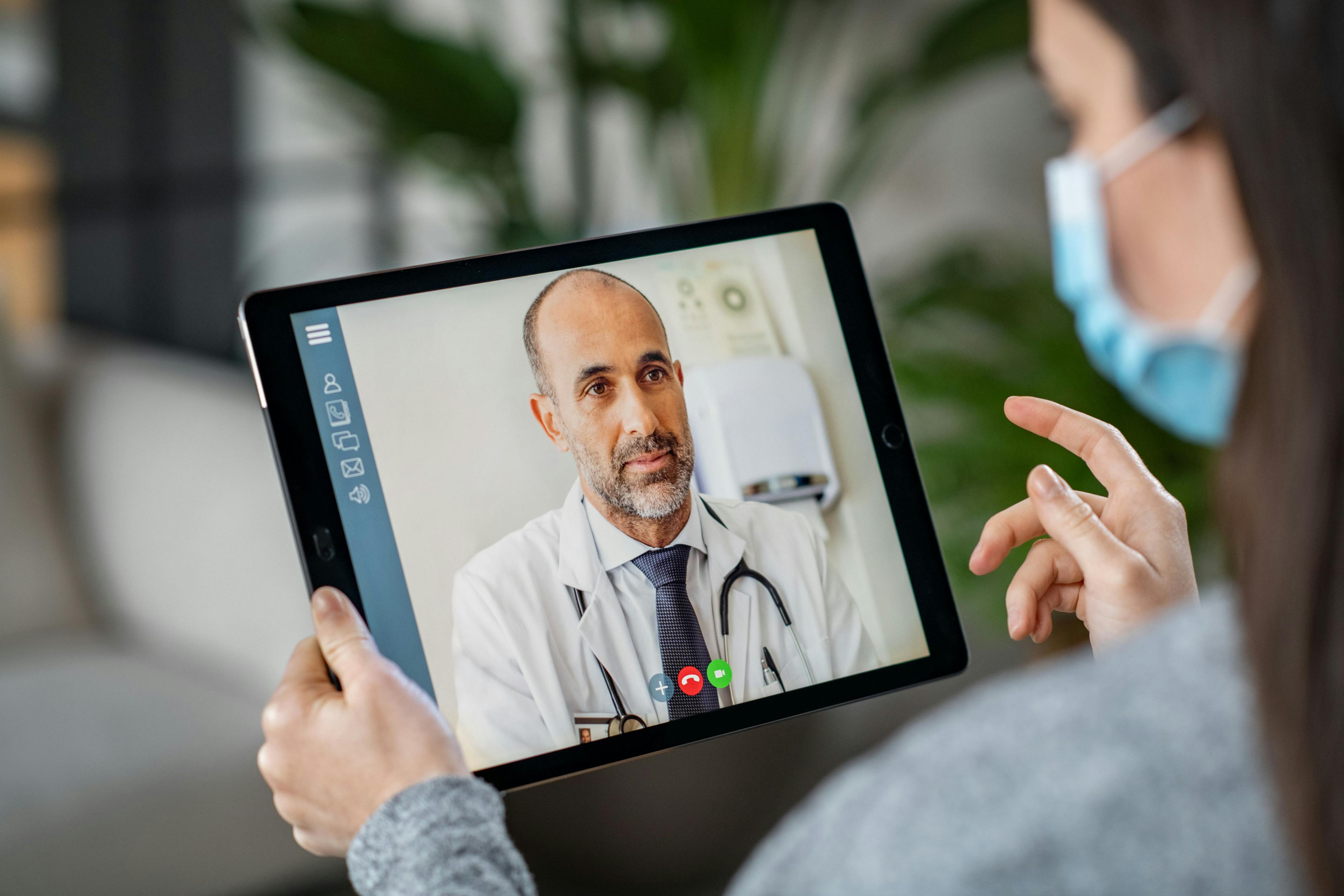 patient wearing face mask on virtual call with doctor