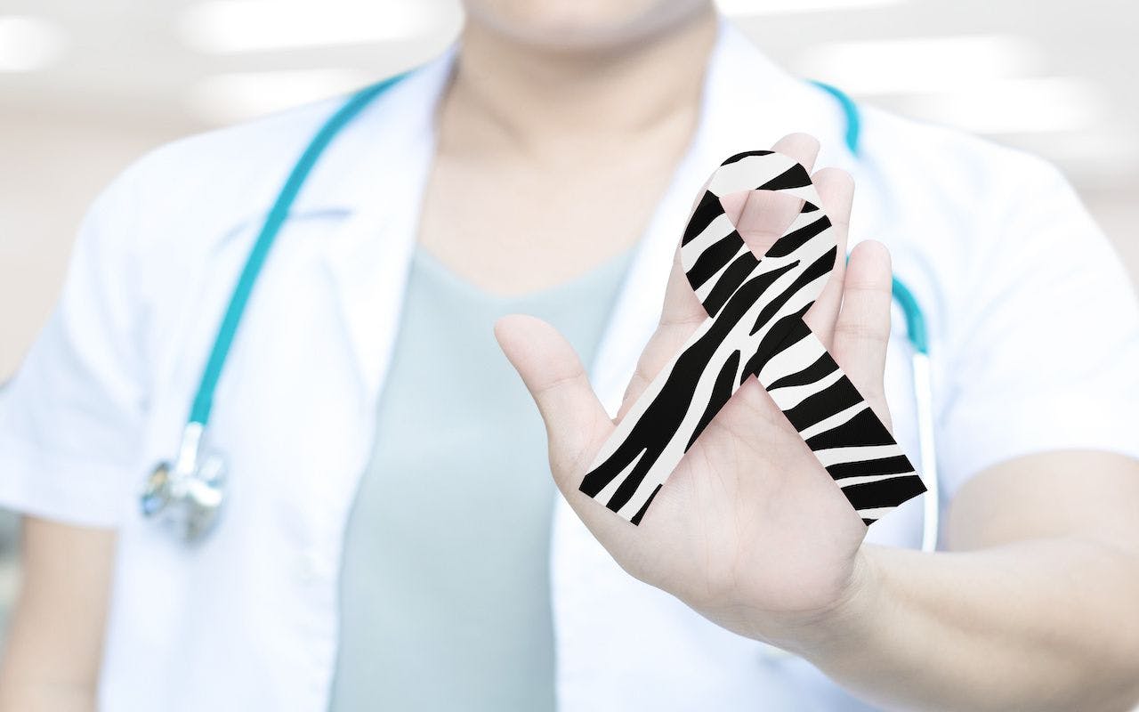 Carcinoid Cancer Awareness rare disease ribbon zebra stripe pattern on doctor hand: © Khunatorn - stock.adobe.com