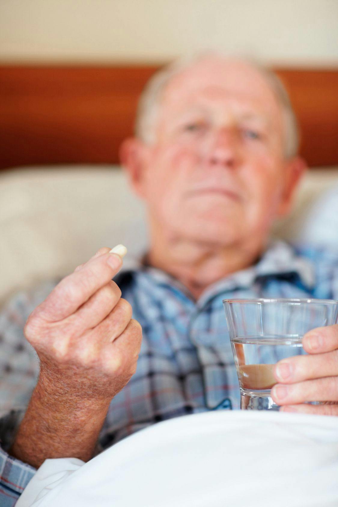 Older man holding pill