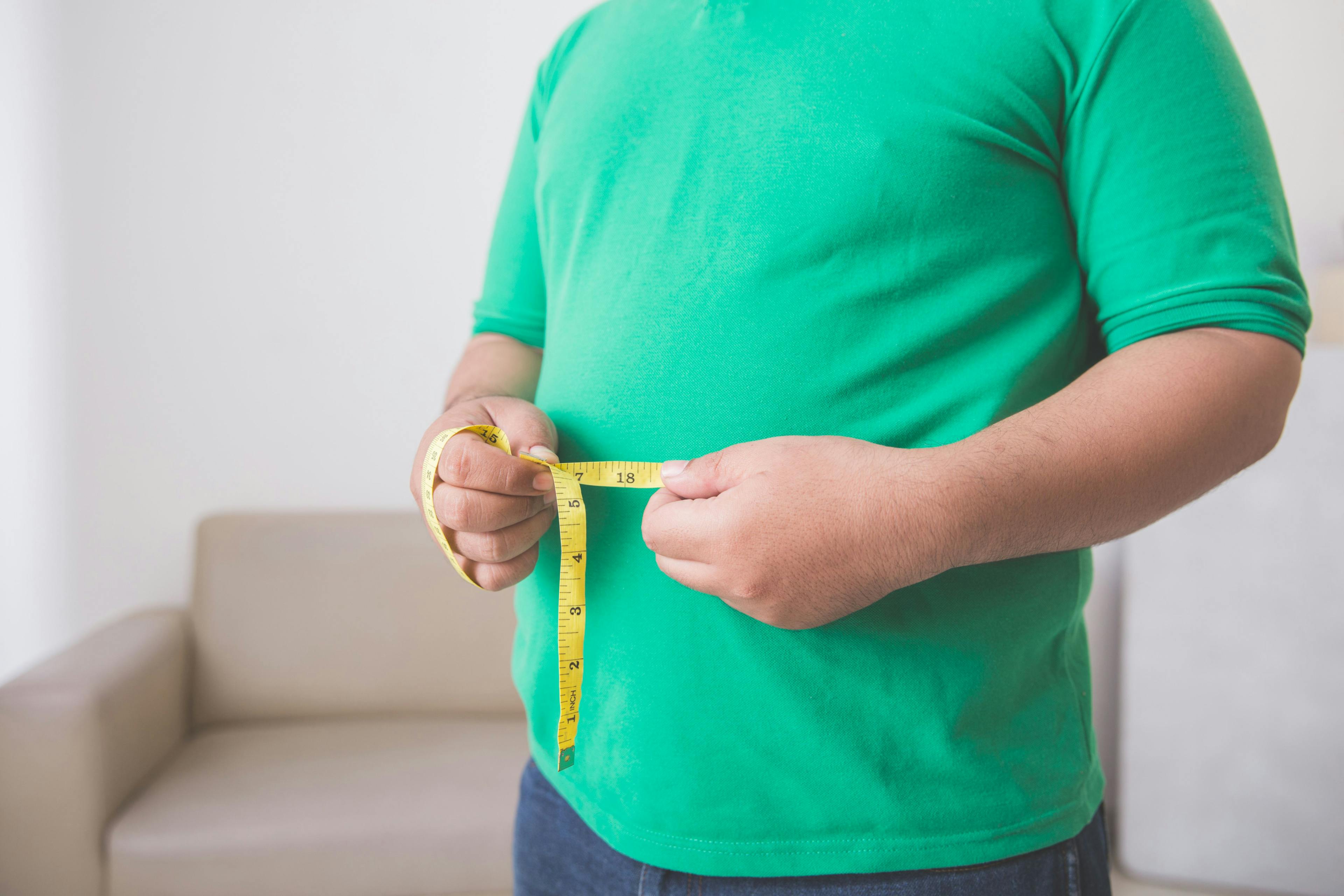 man holding measuring tape around waist