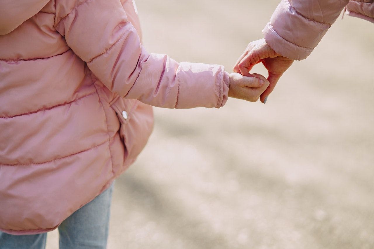 Young child holding hands with adult.