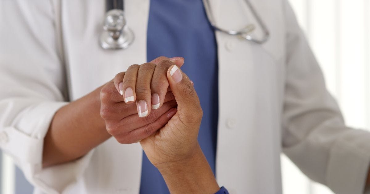Closeup of Black doctor holding patient's hand