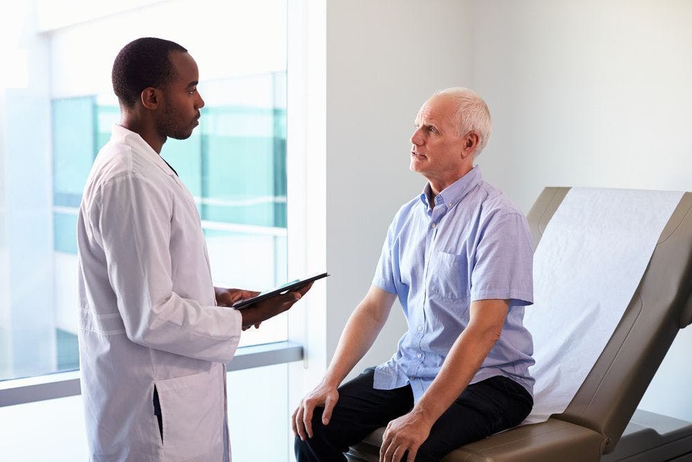 Older White patient speaking with Black doctor