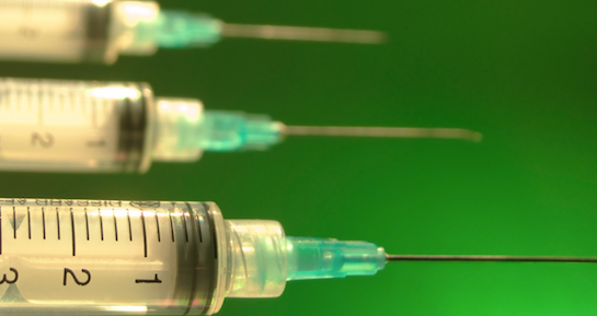 several syringes over a bright green background