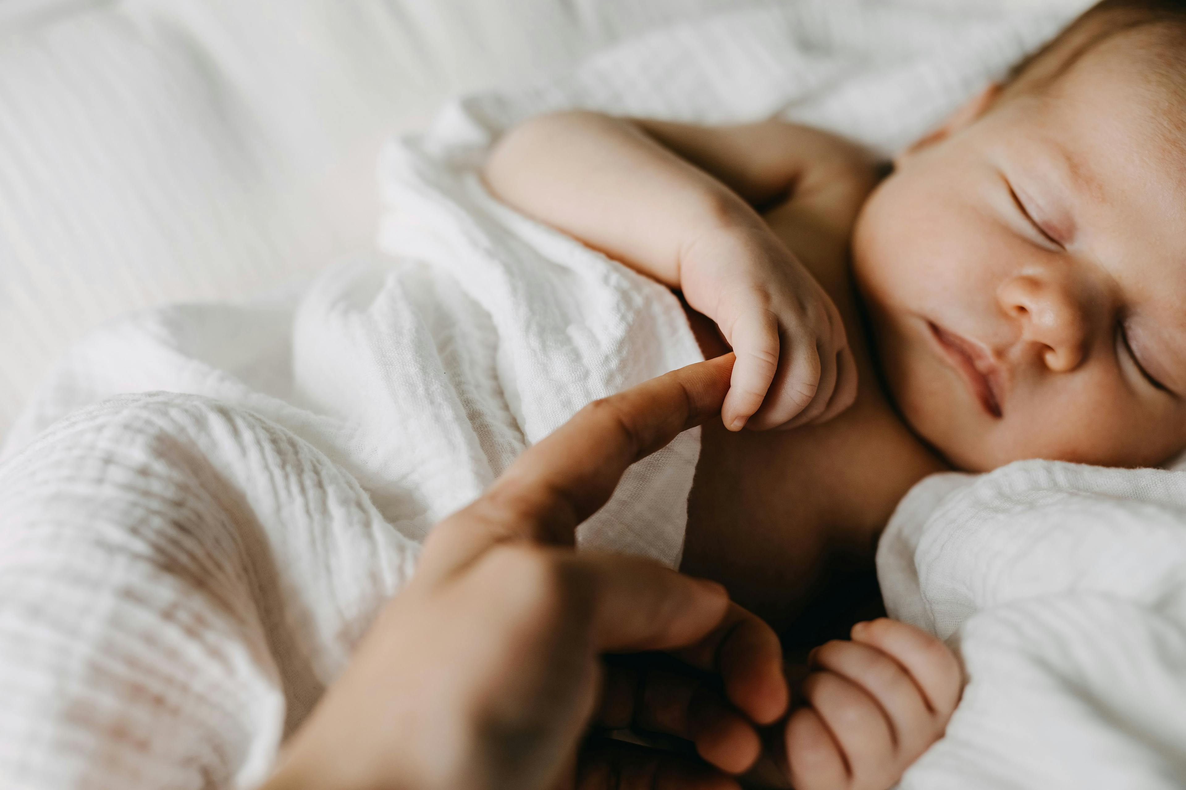 sleeping infant holding mother's finger | Image Credit: Bostan Natalia - stock.adobe.com