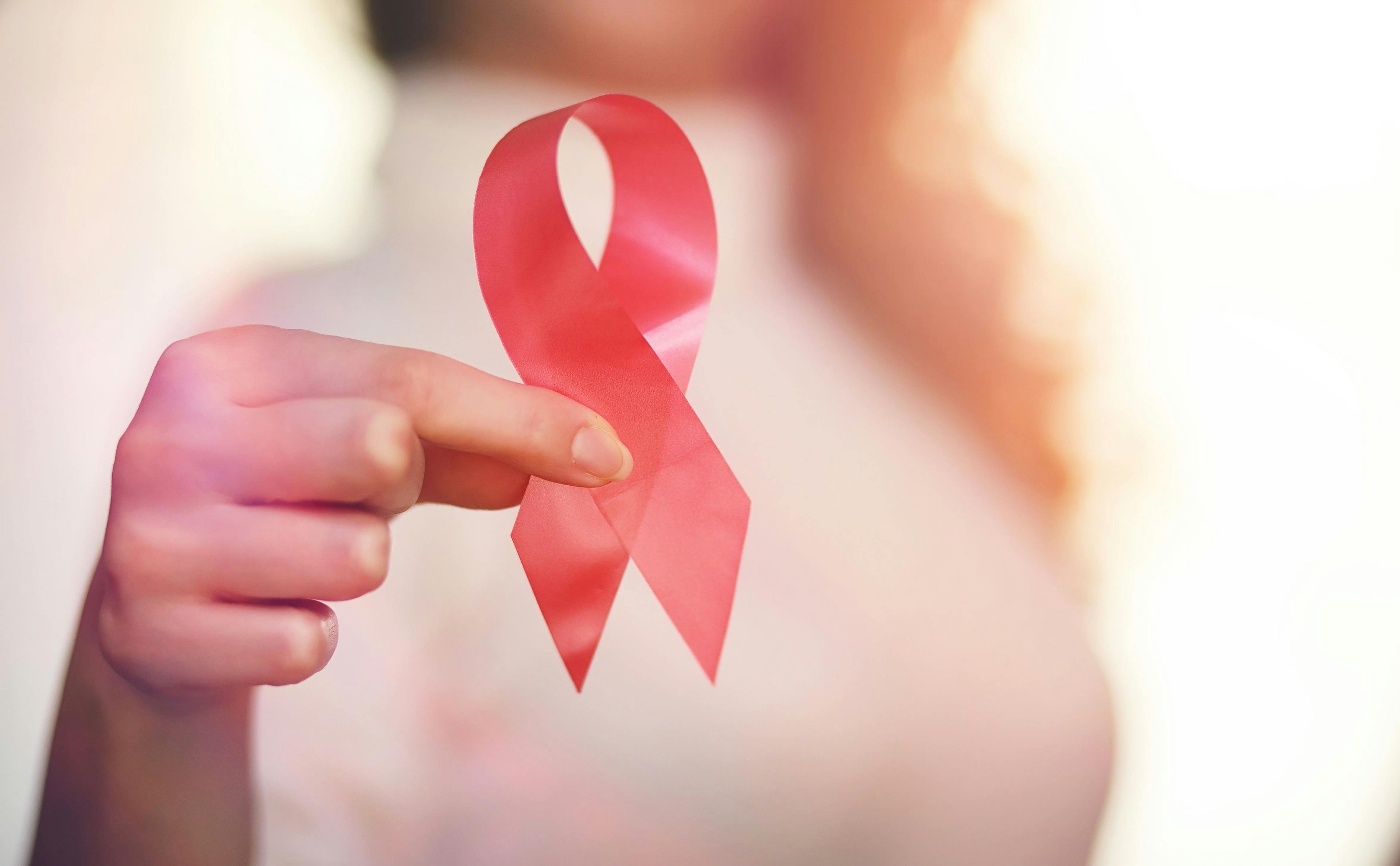 woman holding red HIV ribbon