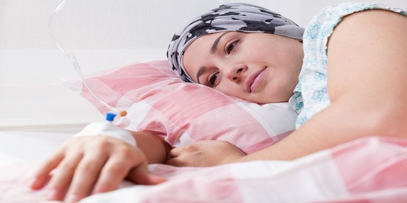 woman with bonnet laying in bed receiving IV in her hand